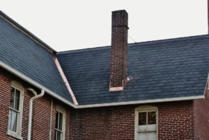dark slanted roof on red brick house with chimney