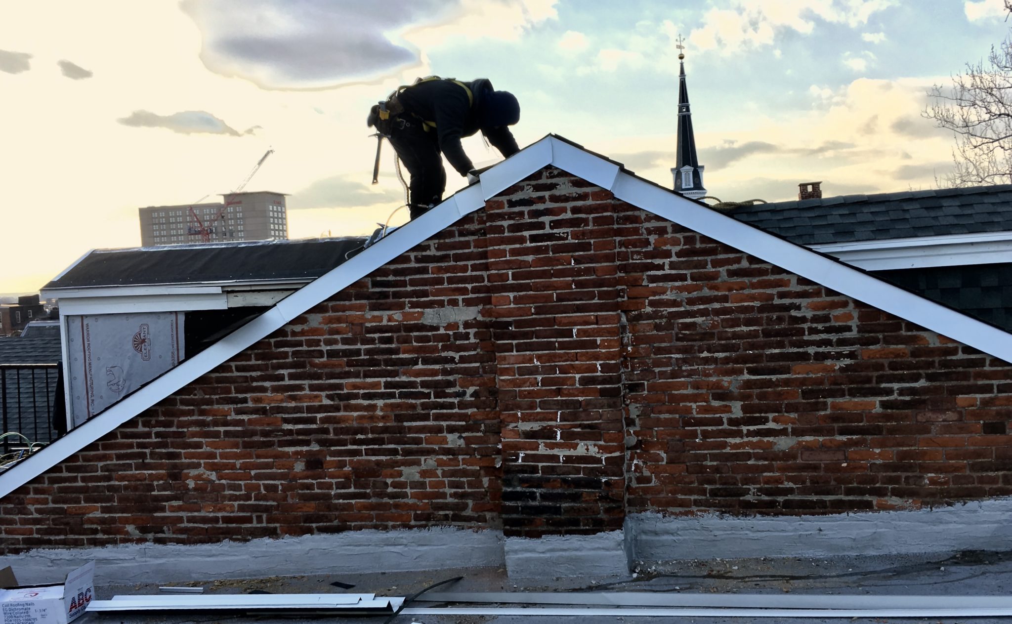 Person in safety equipment on top of a slanted roof