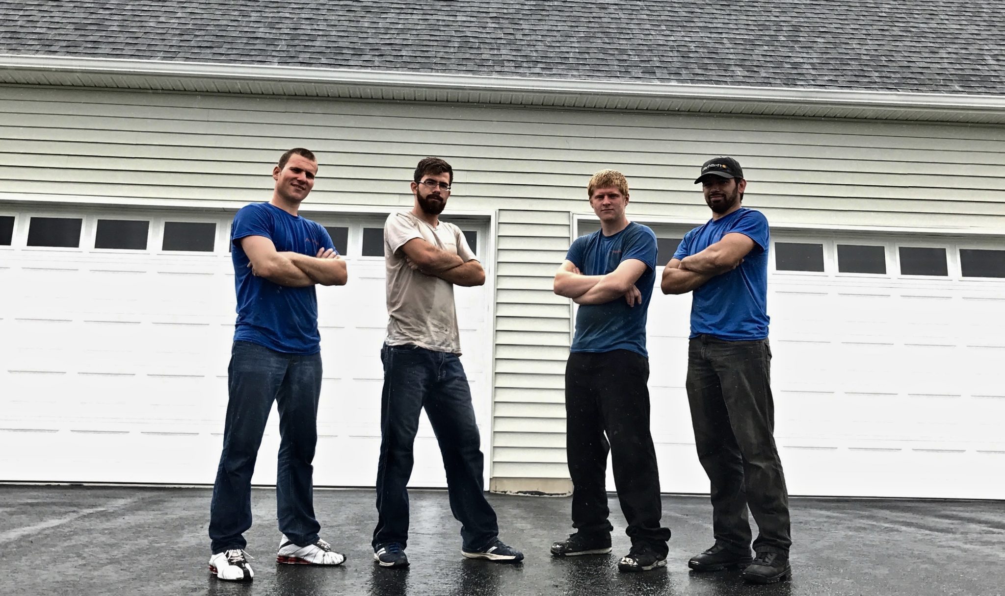 4 men standing in front of two white garage doors
