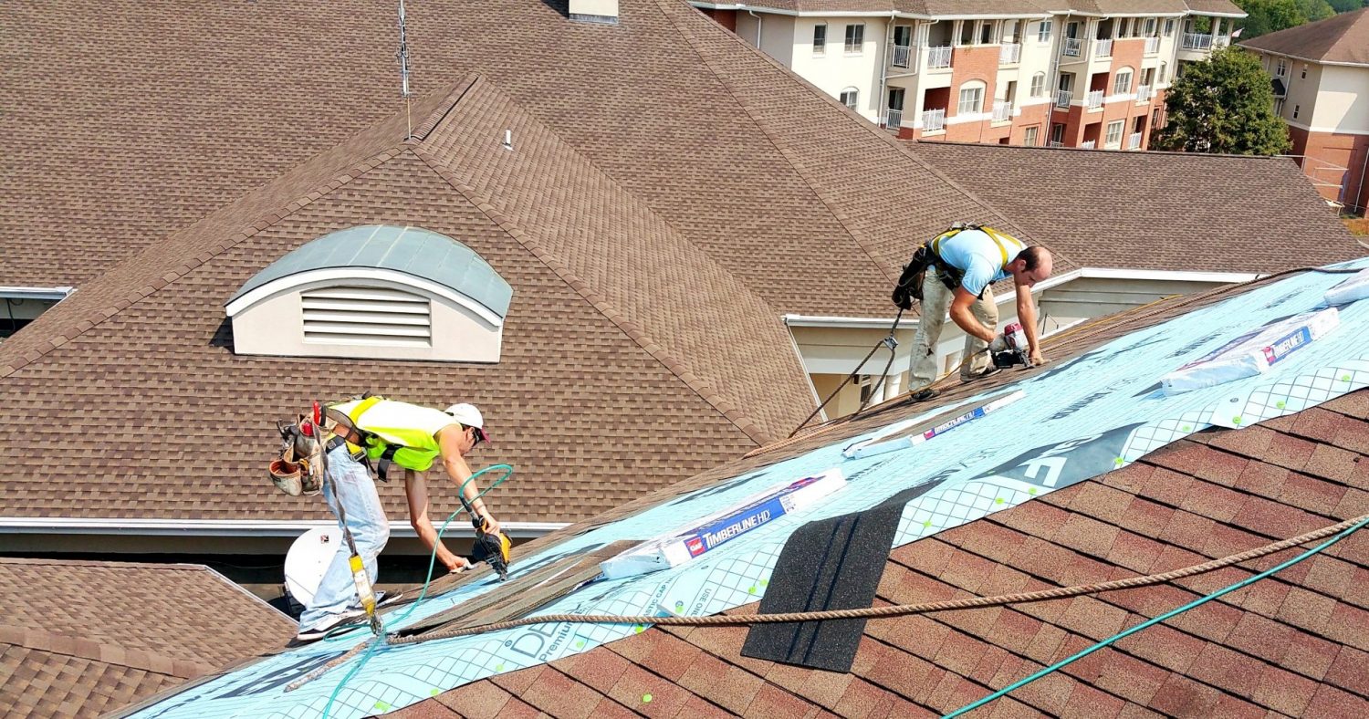 two Joyland roofing employees on a slanted roof installing roofing system