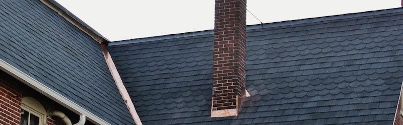 dark slate roofing on red brick house with a chimney