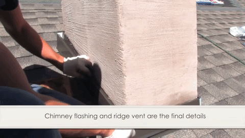 person putting chimney flashing and ridge went on chimney on top of roof
