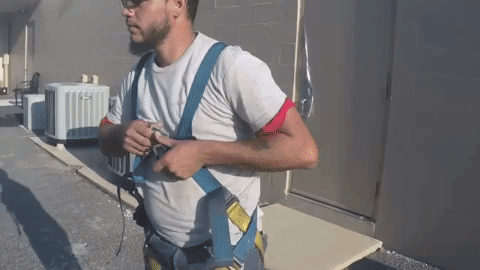 Man putting on safety harness for roofing work