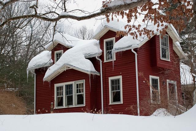 red vinyl siding home with a snow covered roof