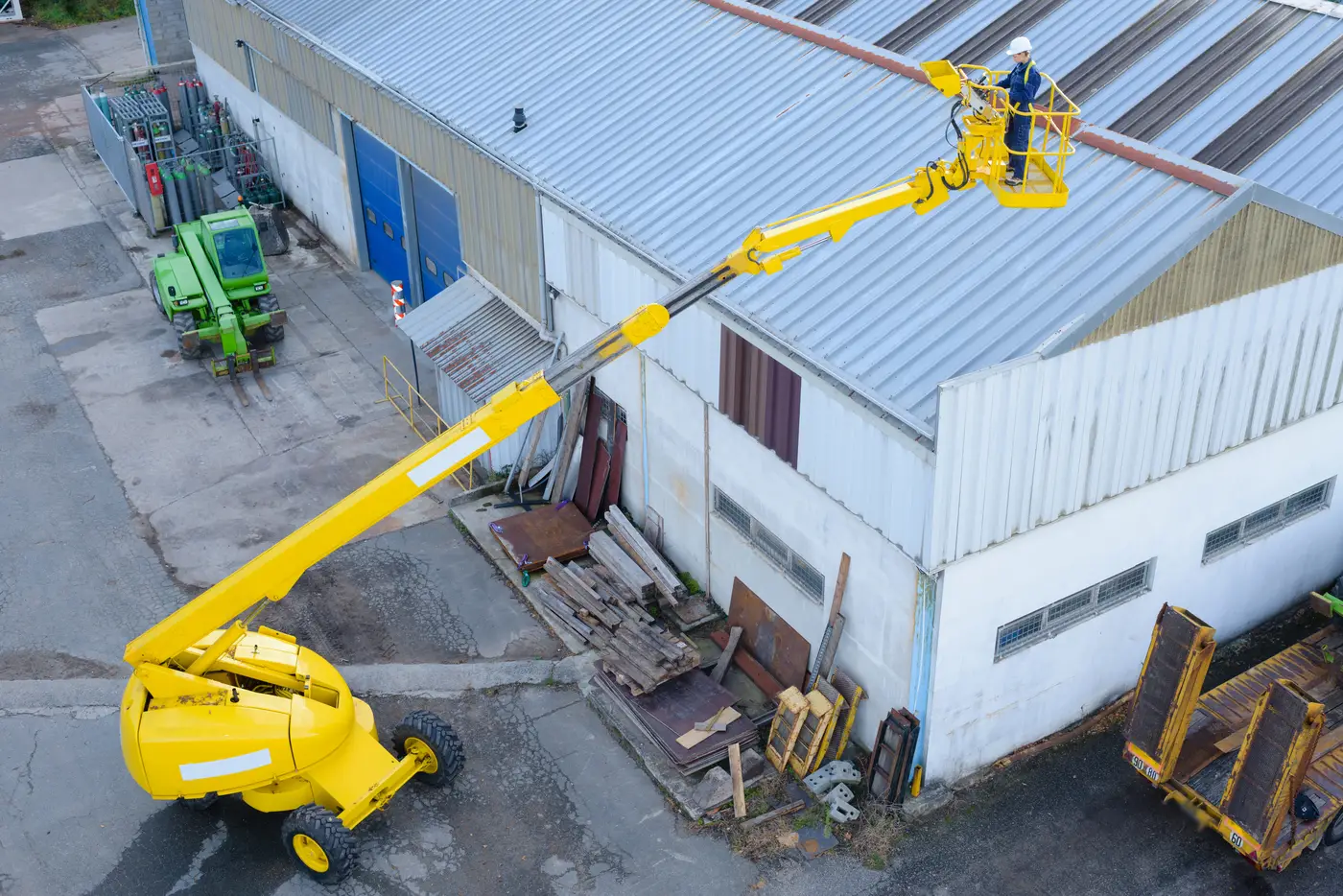 Large white warehouse roof being fixed with yellow cherry picker