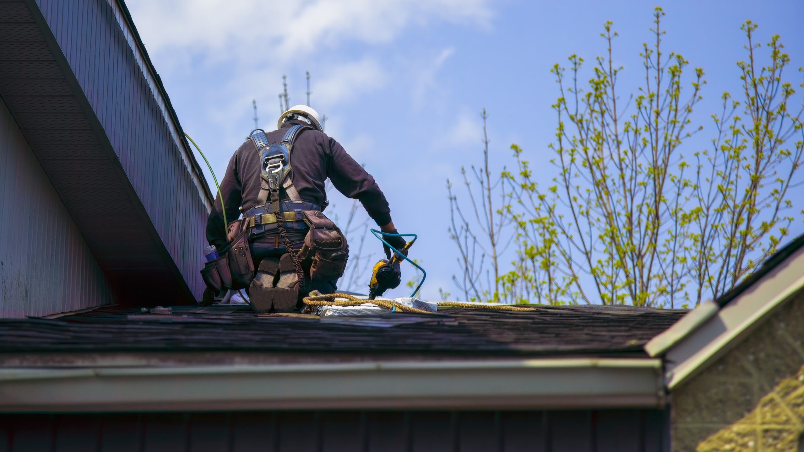 Man in safety gear performing roof repairs on home in York County, PA