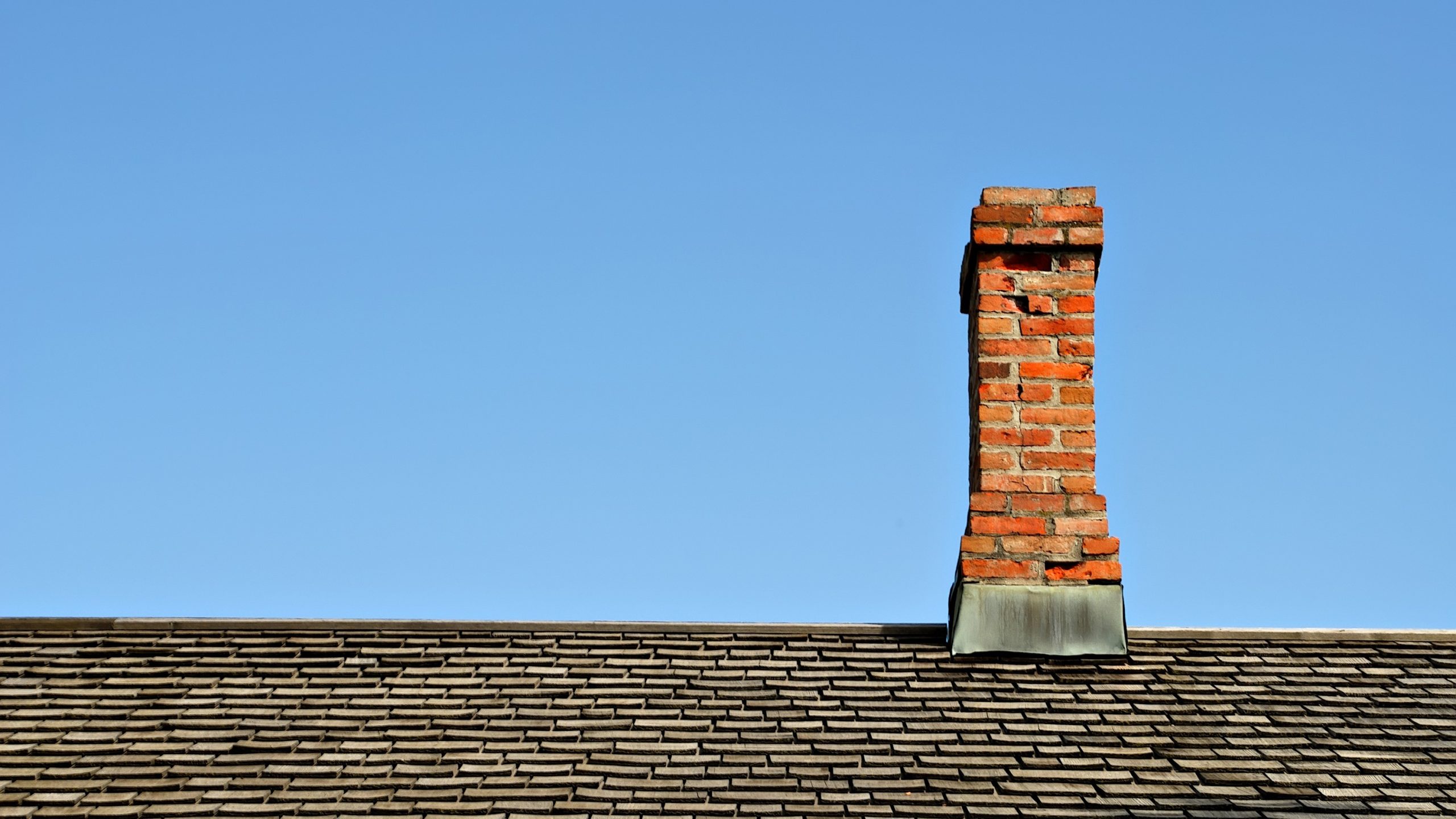 Dark gray asphalt roof with brick chimney of home in Mechanicsburg, PA