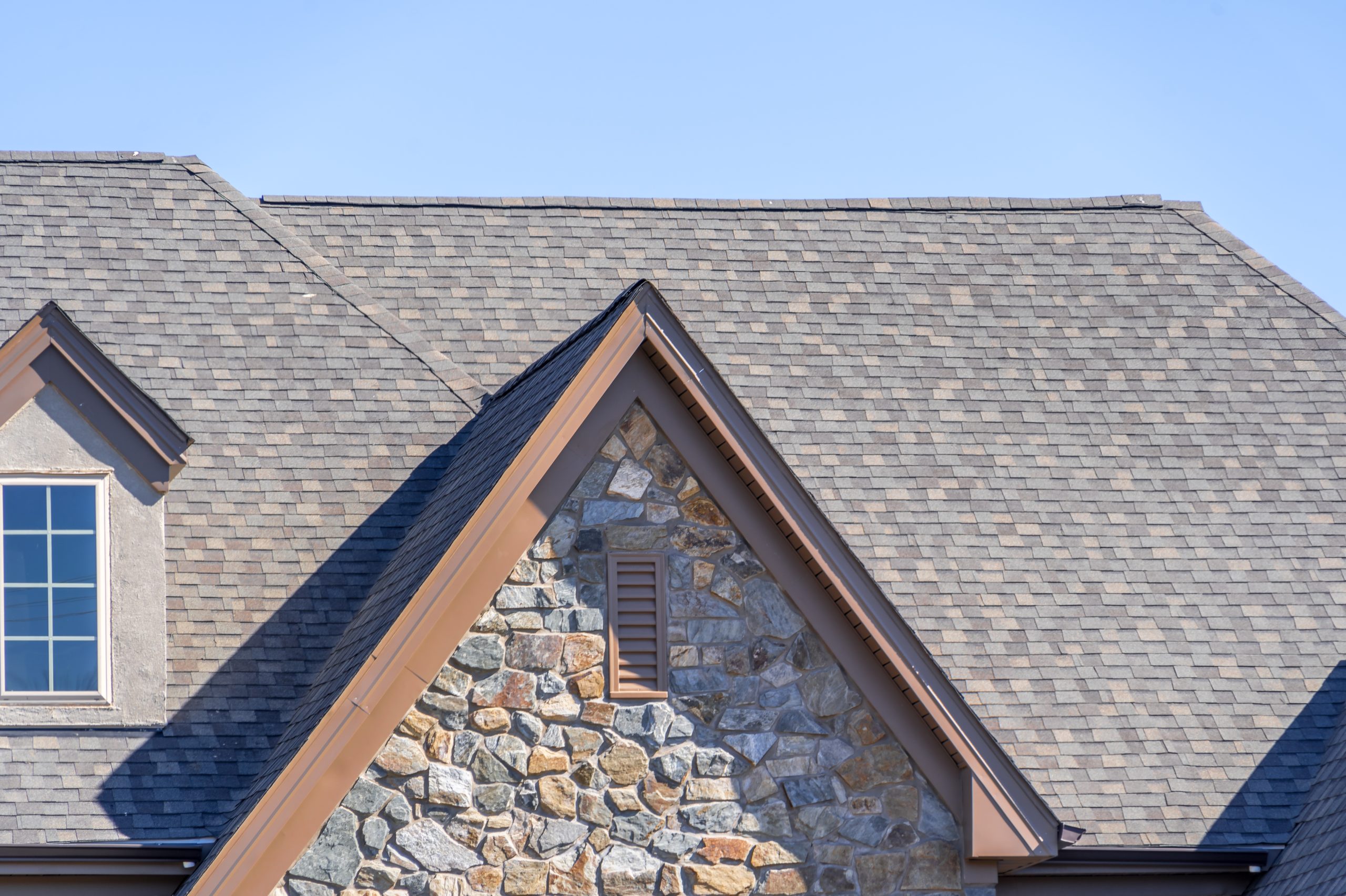 Alps-style gable asphalt roof with stone siding and attic window