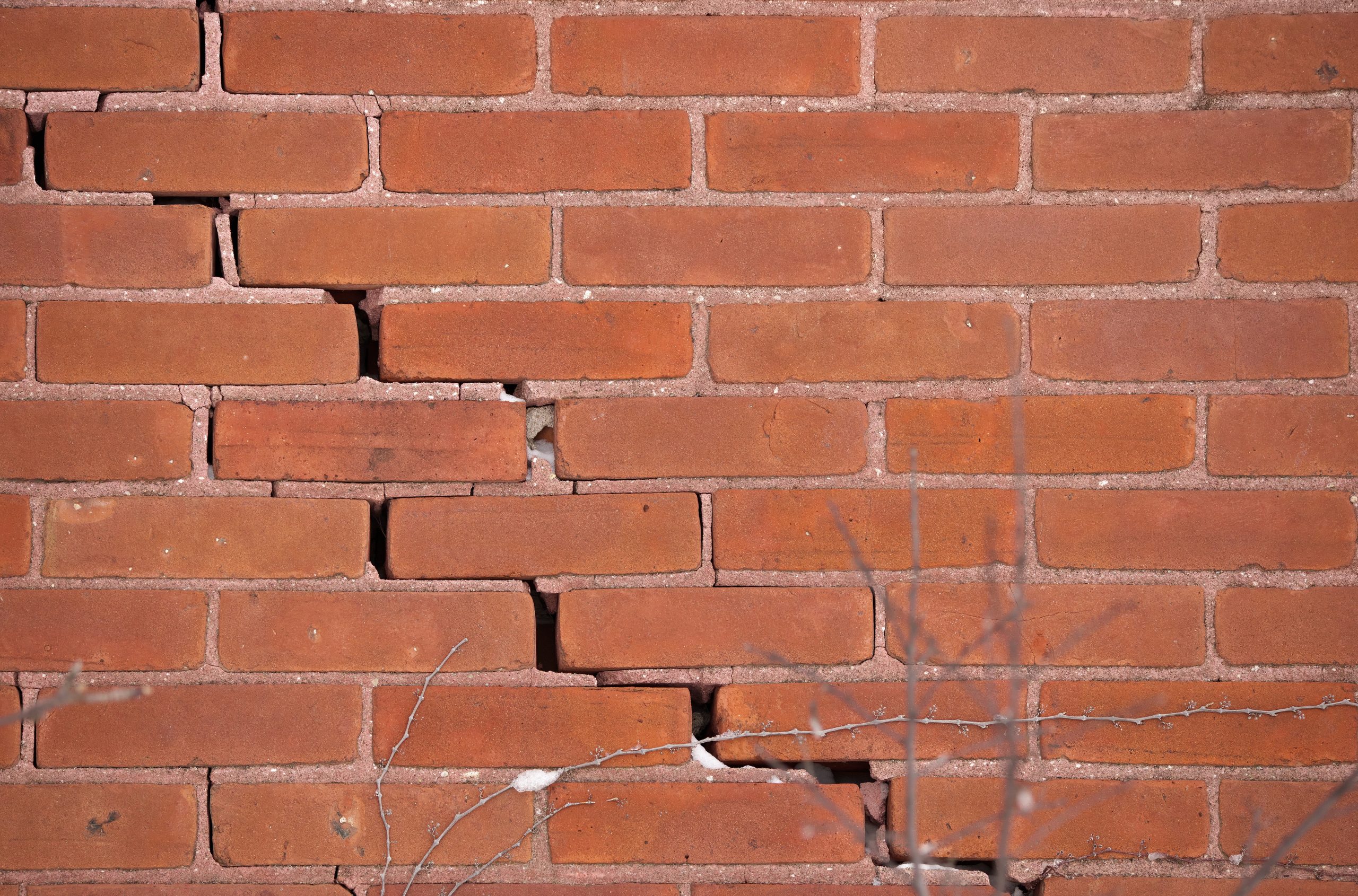 Red brick wall with crumbling mortar and large crack