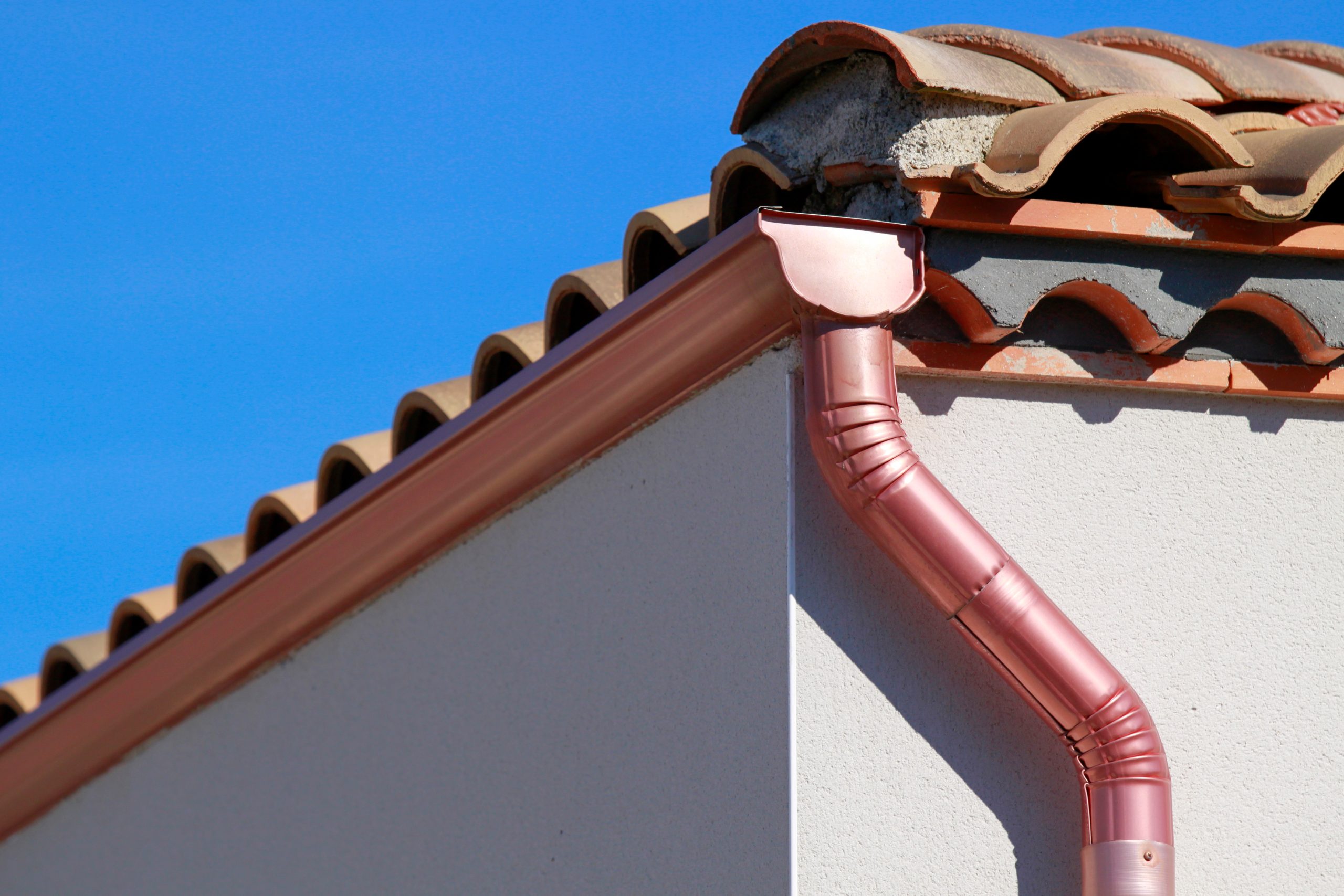 Close-up of copper seamless gutters on Spanish-style house, blue sky